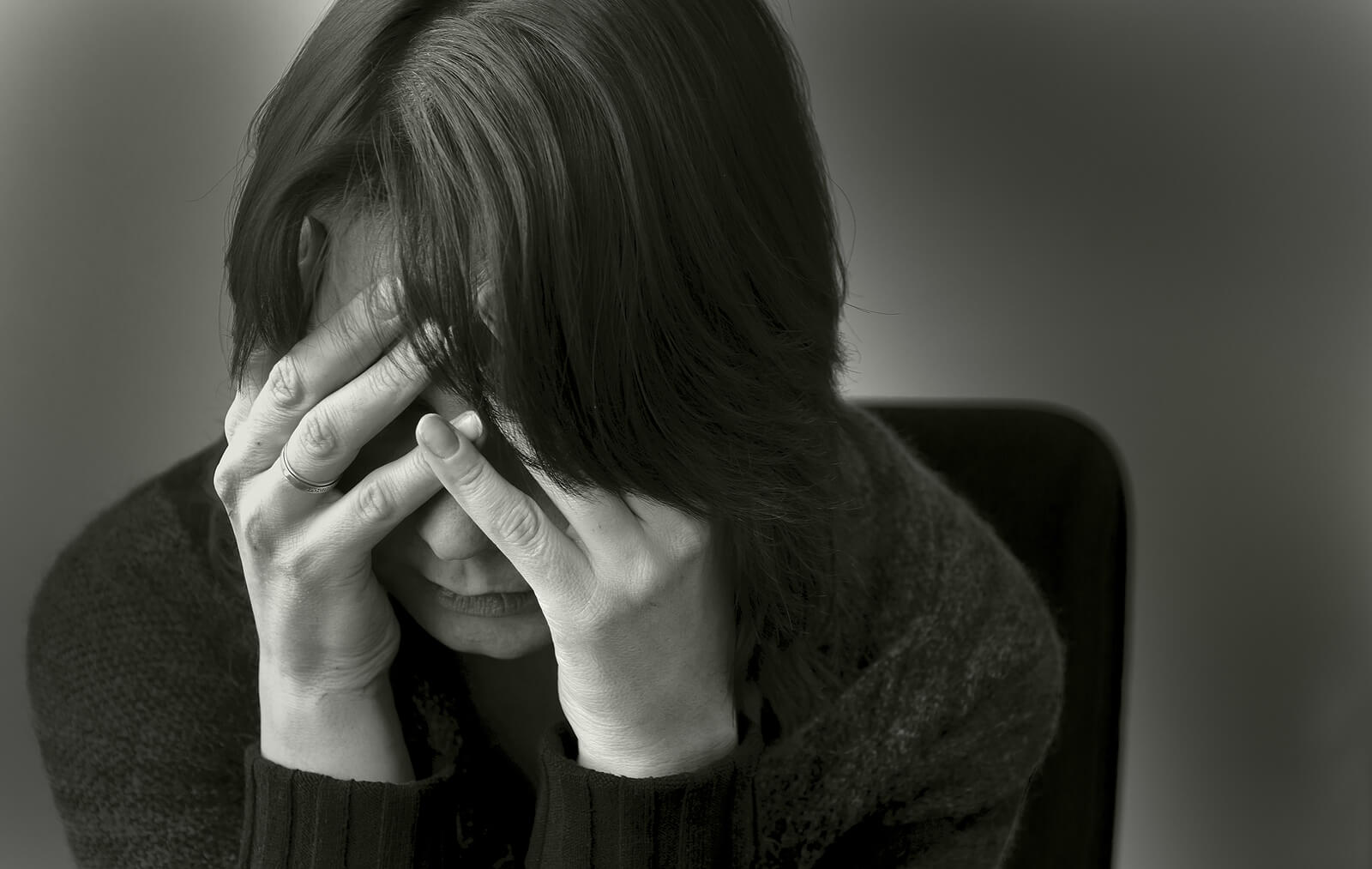 Photo of a woman sitting down holding her head in her hands. This photo represents how depression can feel overwhelming. By meeting with a depression therapist in California you can begin to manage your depression symptoms.