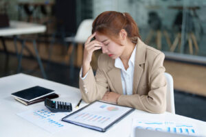 An Asian woman holds her head with a stressed look while working. This could represent the perfectionism an Asian American therapist in San Ramon, CA can help you overcome. Learn more about the support group therapy in San Ramon, CA can offer by contacting an anxiety therapist in California. 