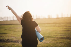A woman holds up a peace sign while holding a yoga mat. Finding support to overcome anxiety is available via online anxiety therapy in San Ramon, CA. Learn more about anxiety therapy in California and how an anxiety therapist in California can help today. 