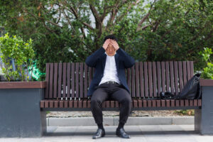 A man sits alone on a park bench with hands on either side of his head. This could symbolize the stress of past trauma that a filipino therapist in San Ramon, CA can help address. Learn more about the support online trauma therapy in California can offer by searching for a trauma therapist in San Ramon, CA today. 